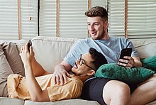 Junges Paar mit Smartphones auf dem Sofa